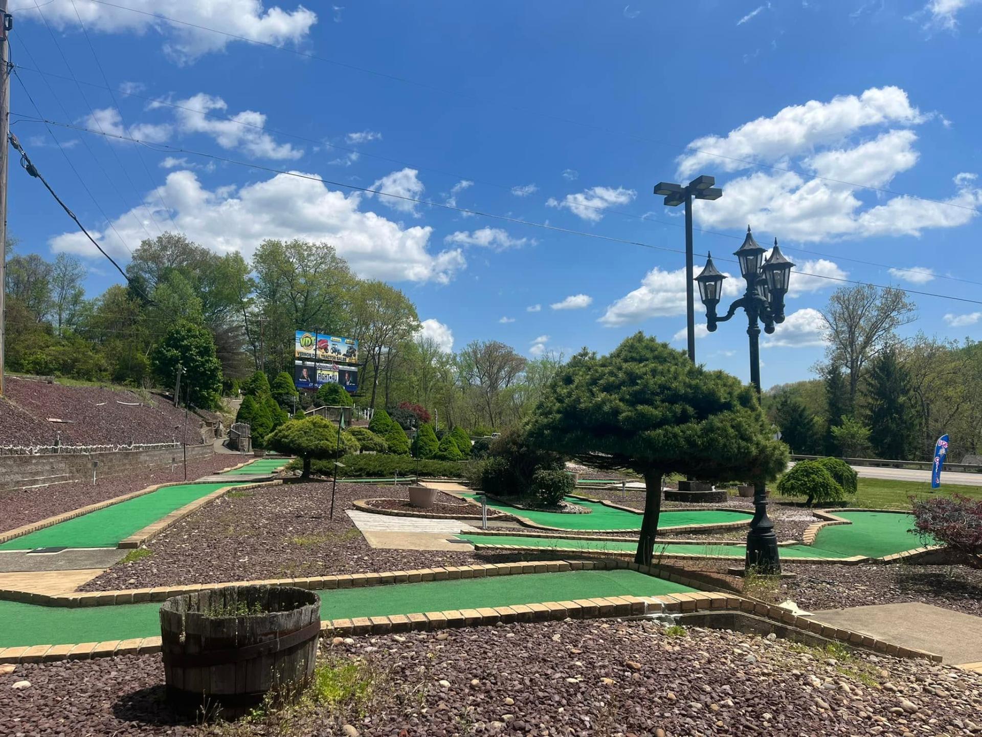 Beautifully landscaped mini golf hole with red flag, rocks and water feature